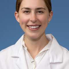 Head shot of Clare Schrodt, MD in white lab coat, smiling at camera