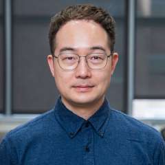 Headshot of Doctor Young Do Koo in a blue button-down shirt and wearing glasses