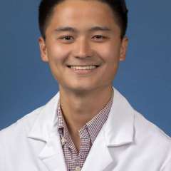Dr. Matthew Du smiling at camera in a white coat