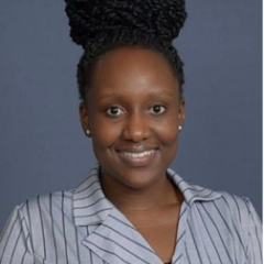 Headshot of a person with braided hair, wearing a striped shirt against a gray background.