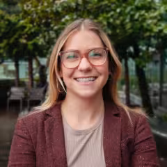Catherine Meyer with blonde hair and glasses wearing a burgundy cardigan and smiling outdoors