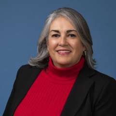 headshot of Aida Alvarez in black blazer and red turtle neck sweater