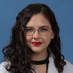 Head shot of Sama Elrahi in white lab coat, smiling at camera