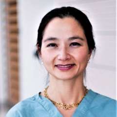 Dr. Tara McCannel headshot, smiling in blue scrubs and gold necklace