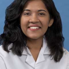 White coat head shot of Darshana Vijaywargiya, smiling at the camera