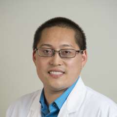 Person in white coat and glasses, professional headshot
